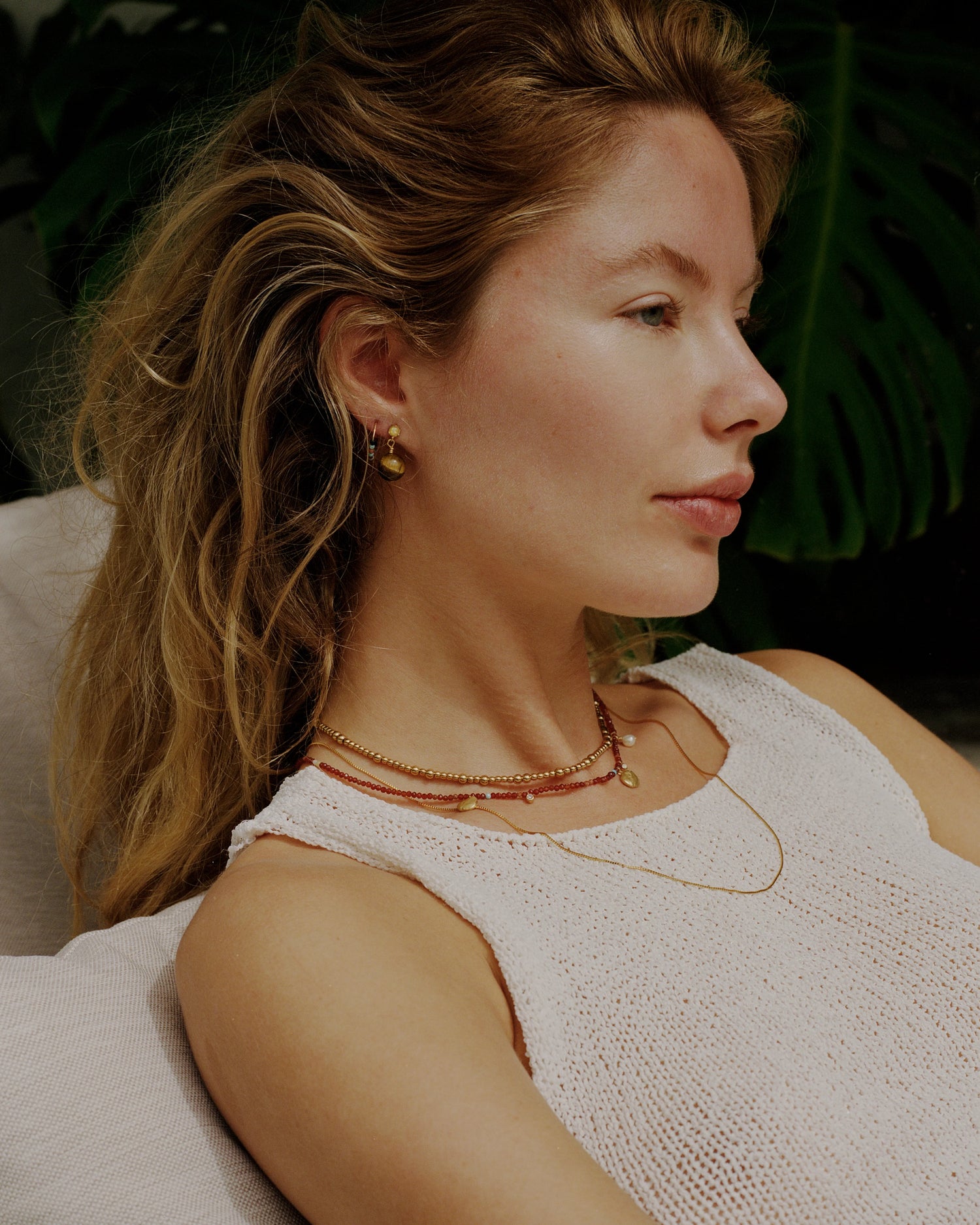 Woman wearing gold jewelry with a blurred green background