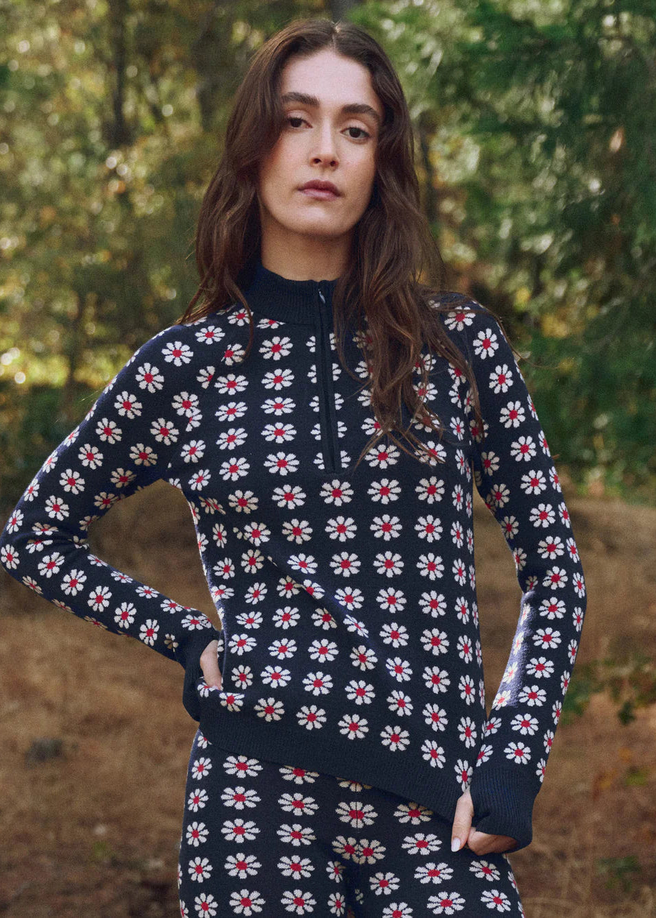 Woman wearing a navy sweater with a red and white floral pattern in an outdoor setting.