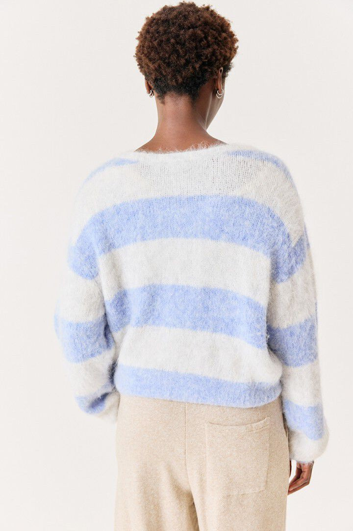 A person shown from the back wearing a fuzzy knit sweater with horizontal light blue and off-white stripes, paired with light beige pants, against a plain light background. - 3