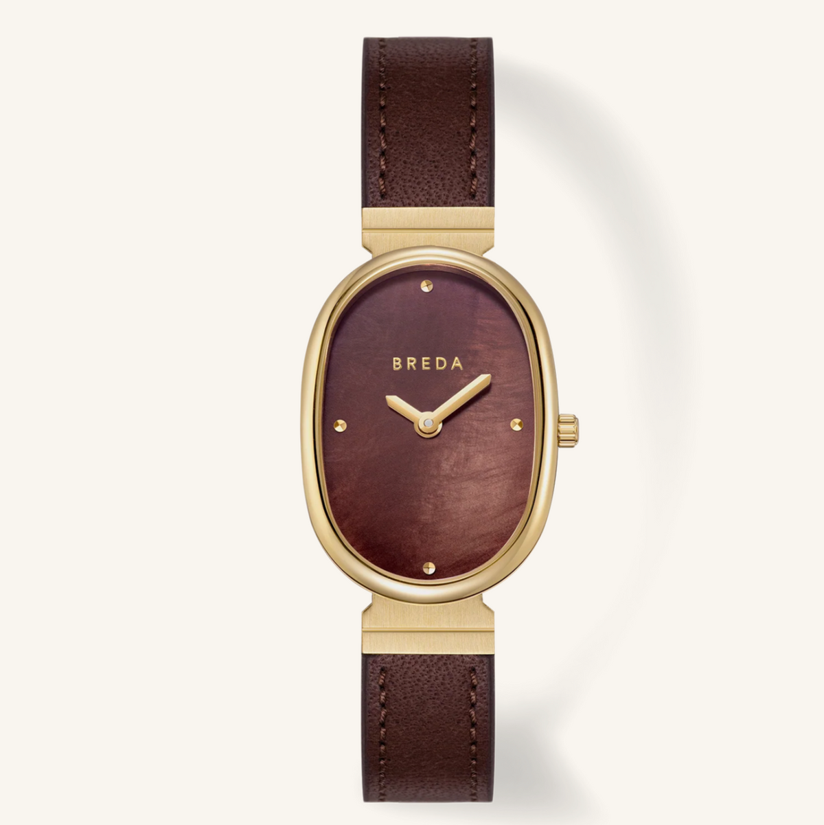 A women's oval wristwatch by Breda, featuring a dark brown leather strap, a gold-tone case, and a matching dark brown dial with gold-tone hands and hour markers.