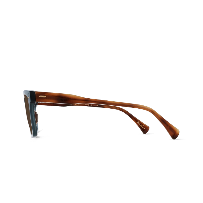 A pair of designer sunglasses with a translucent brown tortoiseshell acetate frame and a contrasting dark blue temple arm, shown in profile against a white background. - 3