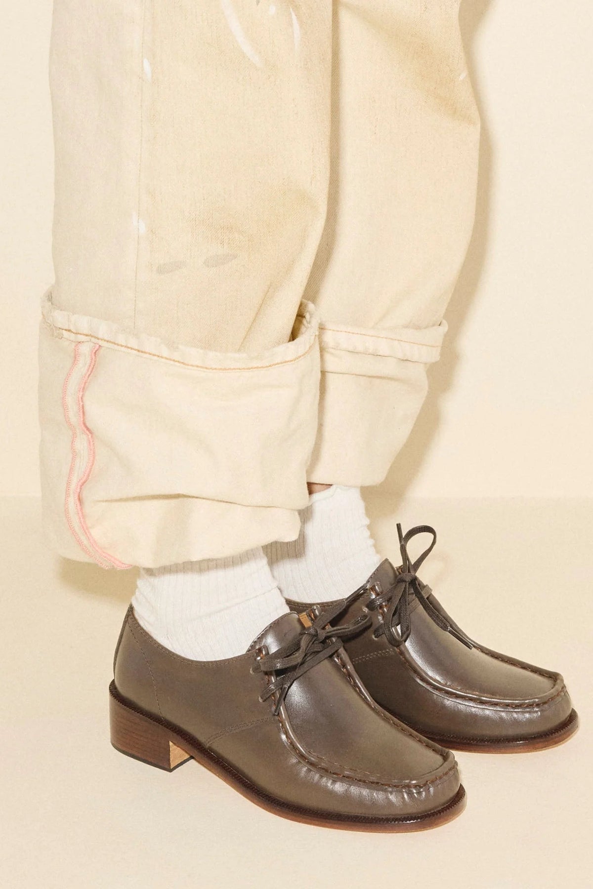 Dark brown leather lace-up shoes with a low block heel, set against a solid cream background. - 2