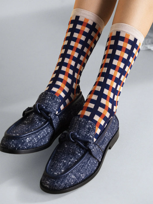 Navy glitter loafers with checkered socks on a light gray background