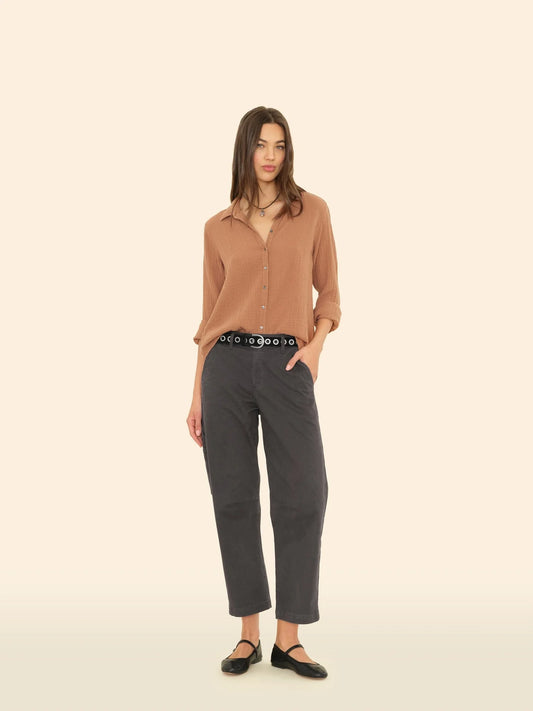 Woman wearing a brown shirt and gray pants on a beige background